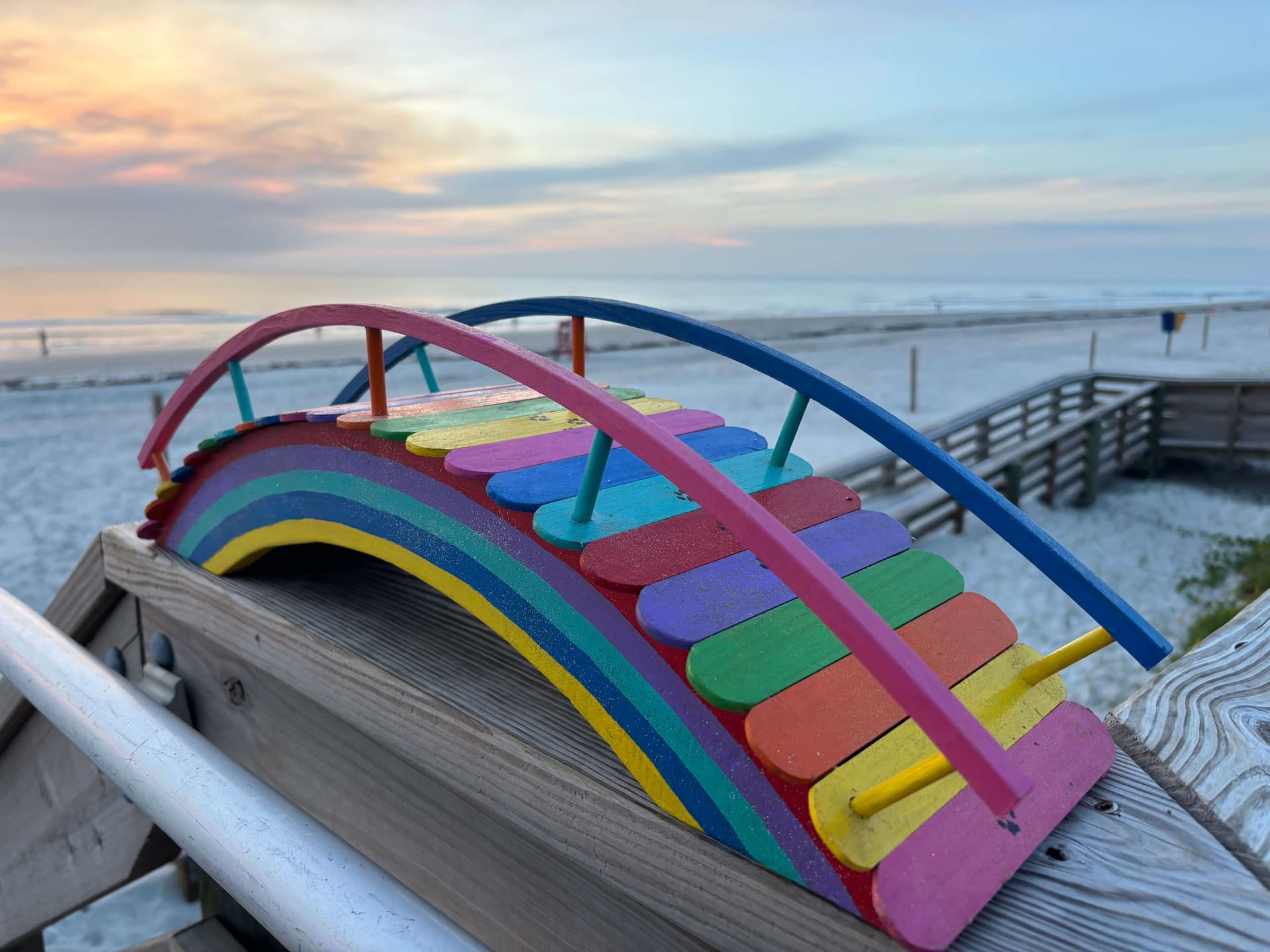 One of Paul Allabaugh's small Rainbow Bridges on the beach at sunrise, full arch catching the golden light