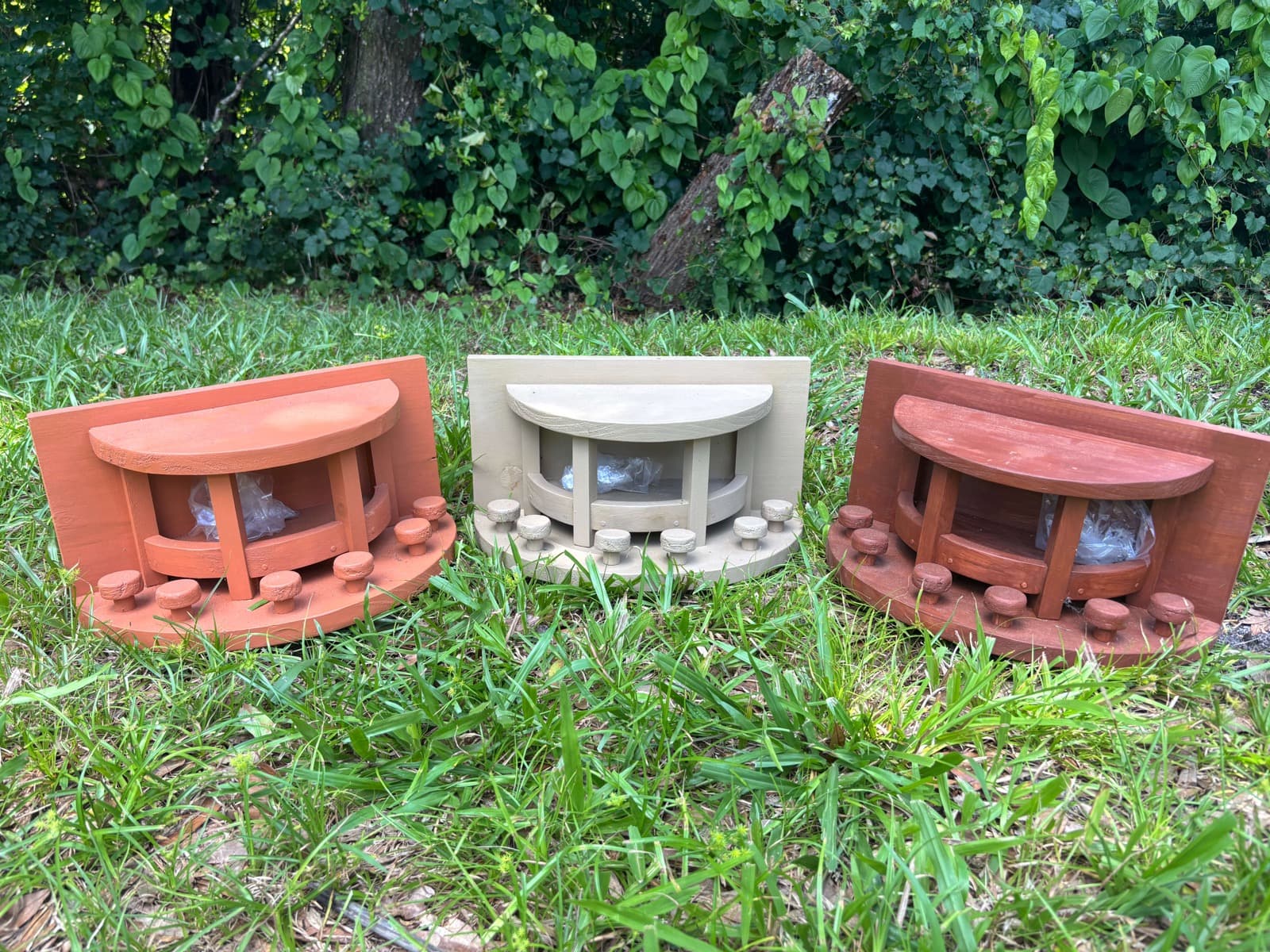 Three handcrafted squirrel feeders in brown, burnt orange, and grey