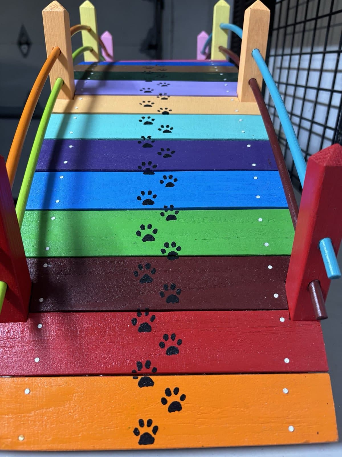 Close-up of paw prints painted across the rainbow planks of Paul Allabaugh's handcrafted bridge