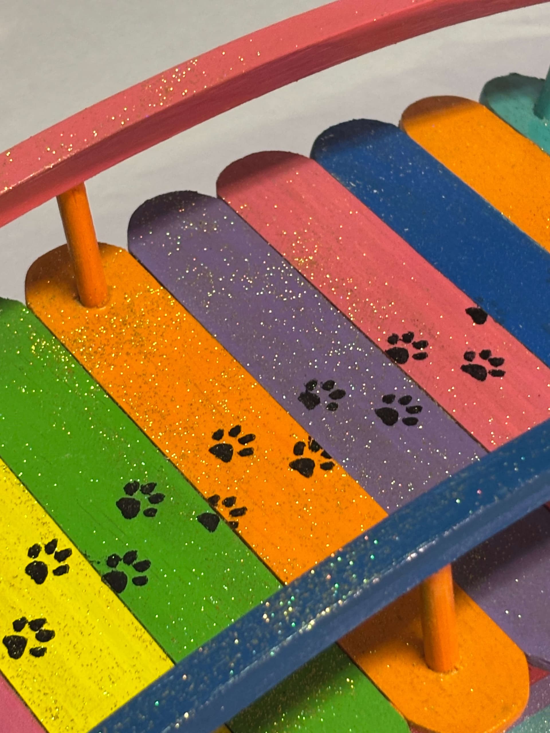 Close-up of hand-painted paw prints and glitter on a rainbow bridge