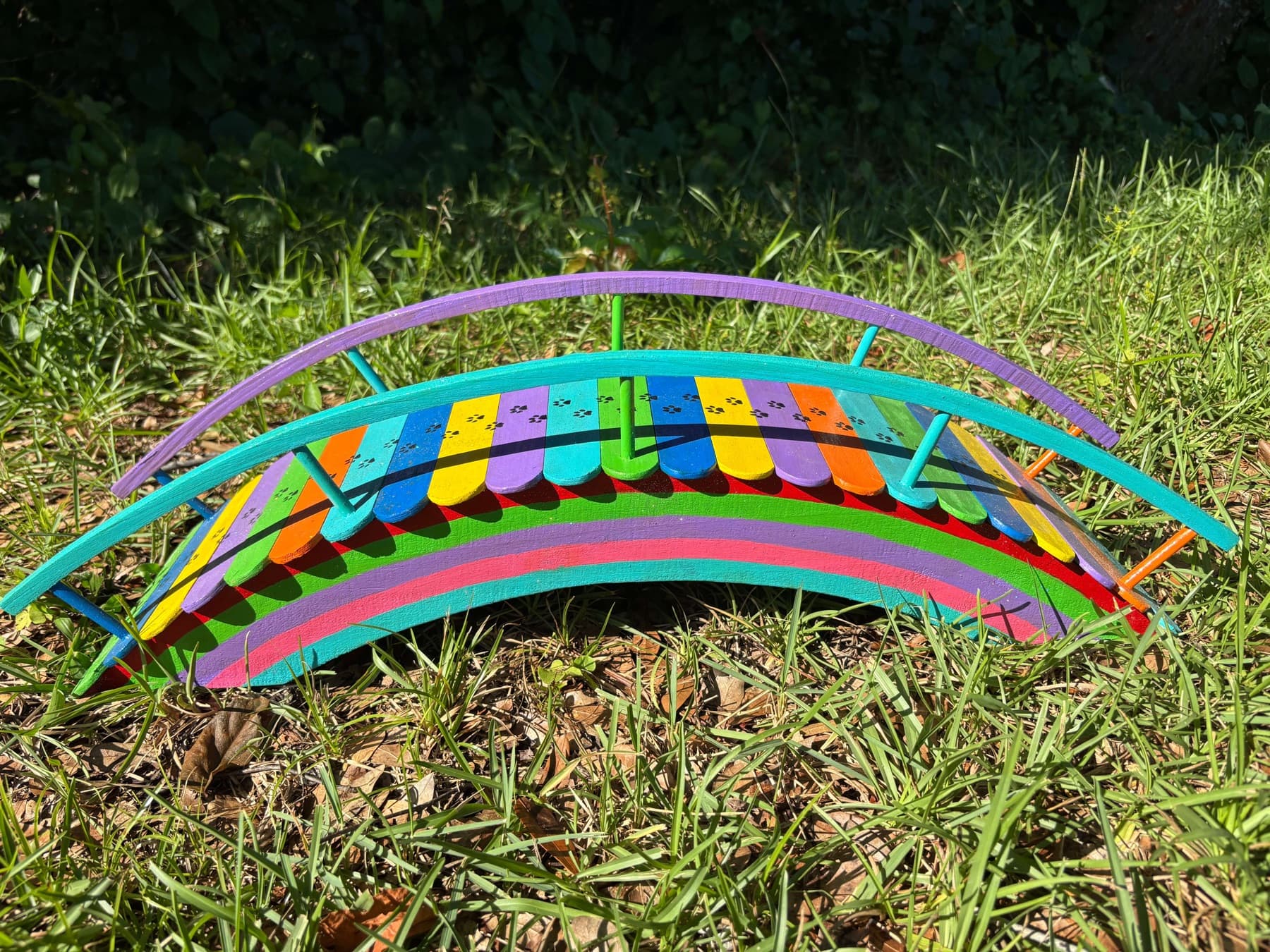 A Rainbow Bridge in the grass, paw prints painted down its deck