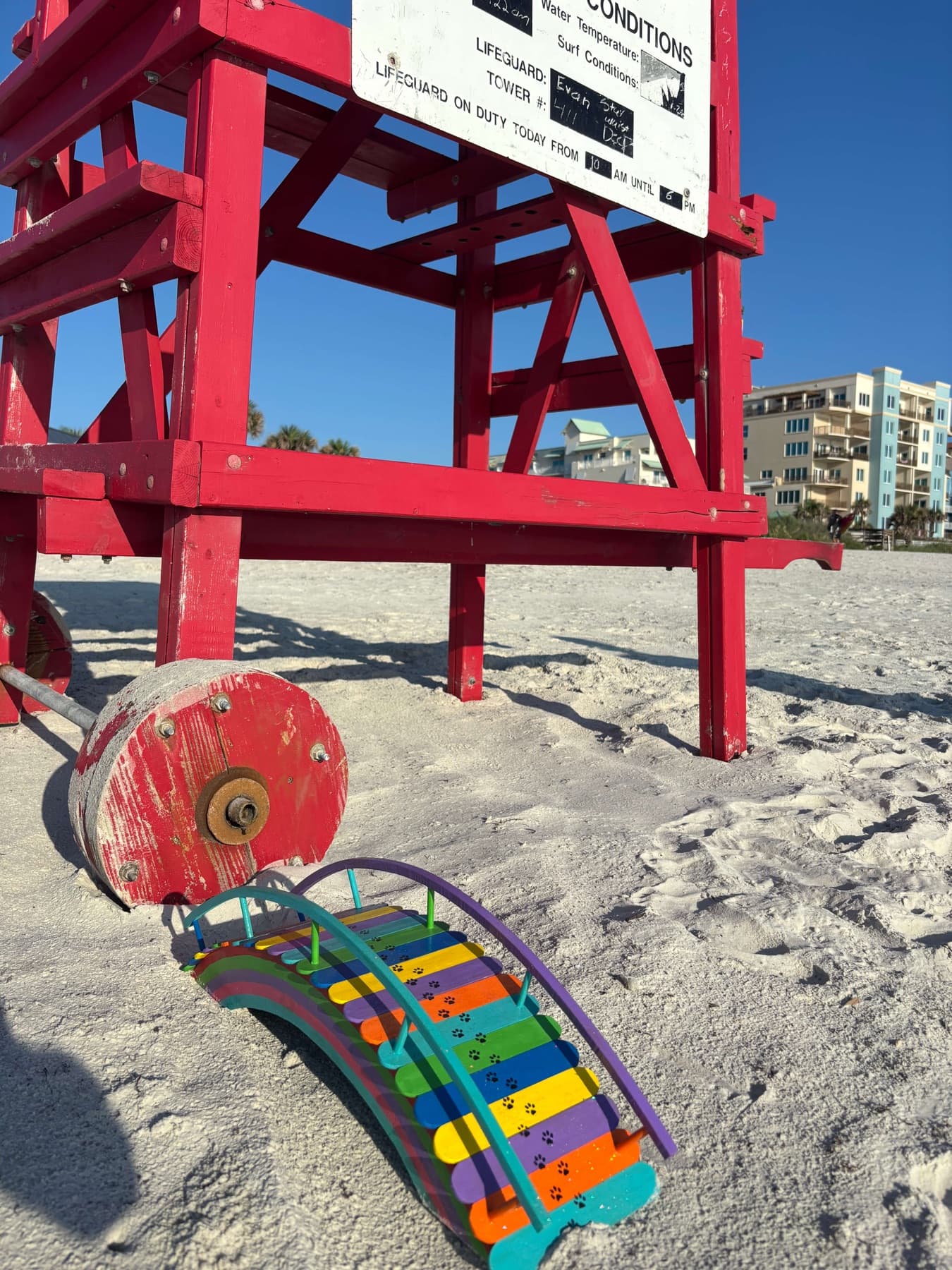 A Rainbow Bridge on the white sand beside a red lifeguard tower
