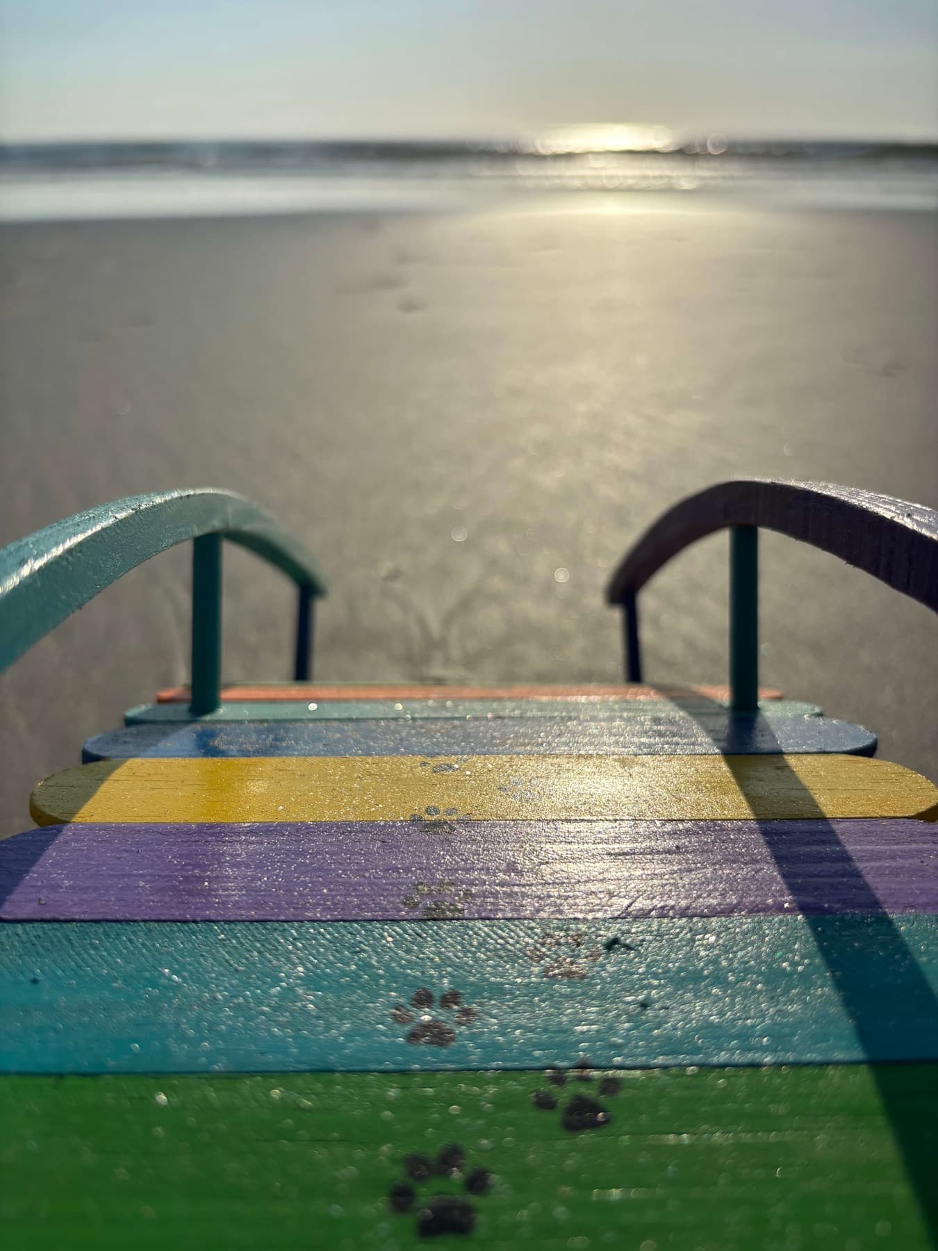 Sunrise over the ocean seen down the paw-printed deck of one of Paul's Rainbow Bridges